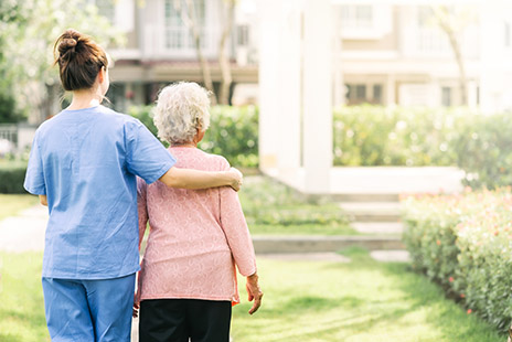 L'infirmiè soutient une personne agée lors d'une promenade